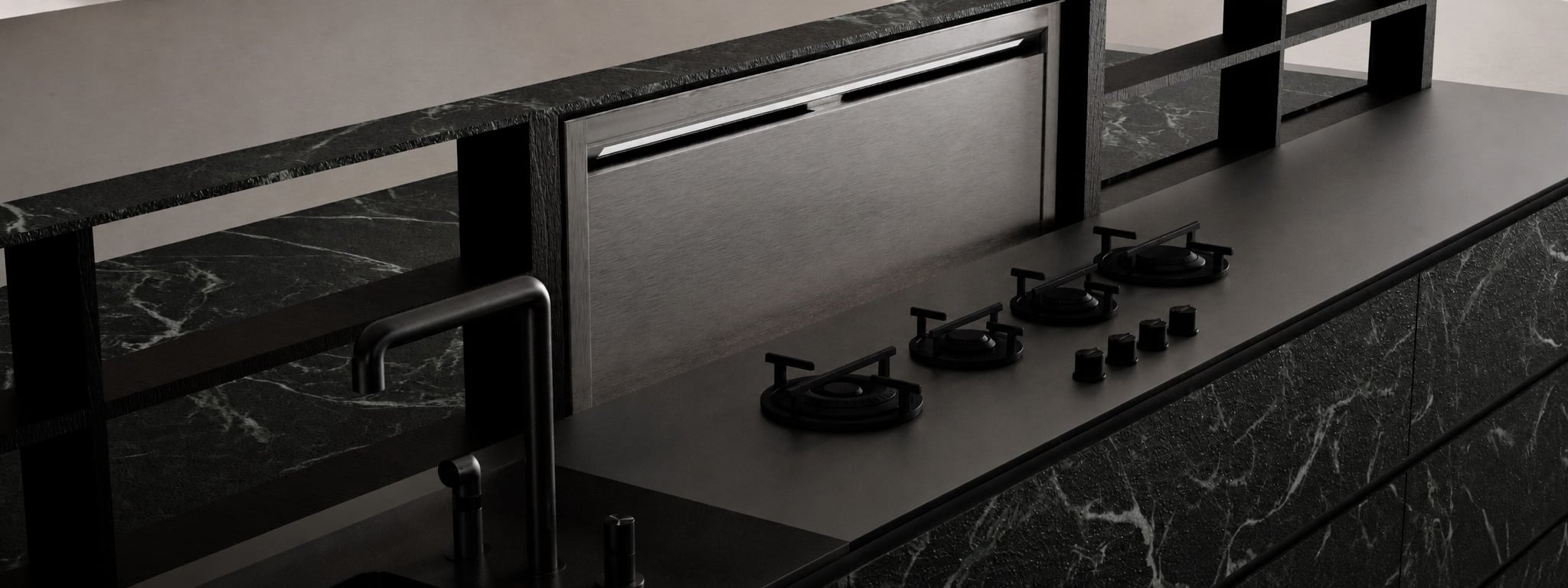 A close detail of a gas hob set into a dark stone island, beneath a veined black marble backsplash.