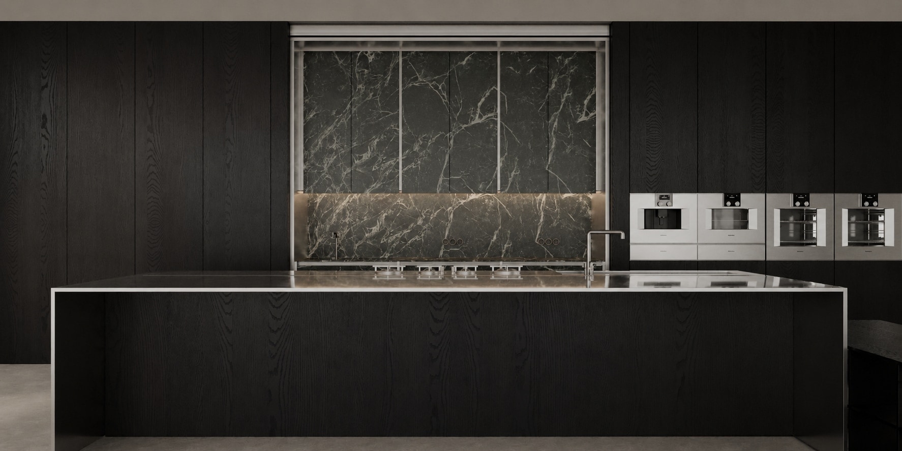 A dark kitchen island with an integrated hob, set against a dramatic black marble splashback and flanking ovens.