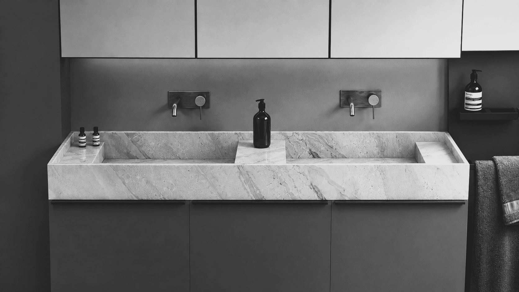 A close frontal view of a double stone trough vanity with wall-mounted taps, mirrored cabinets and charcoal joinery.
