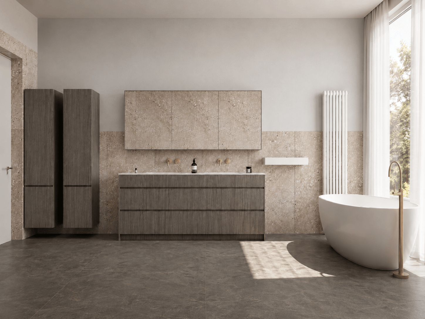 A wide view of a pale stone bathroom with dark timber vanity storage and a freestanding bath beside full-height glazing.