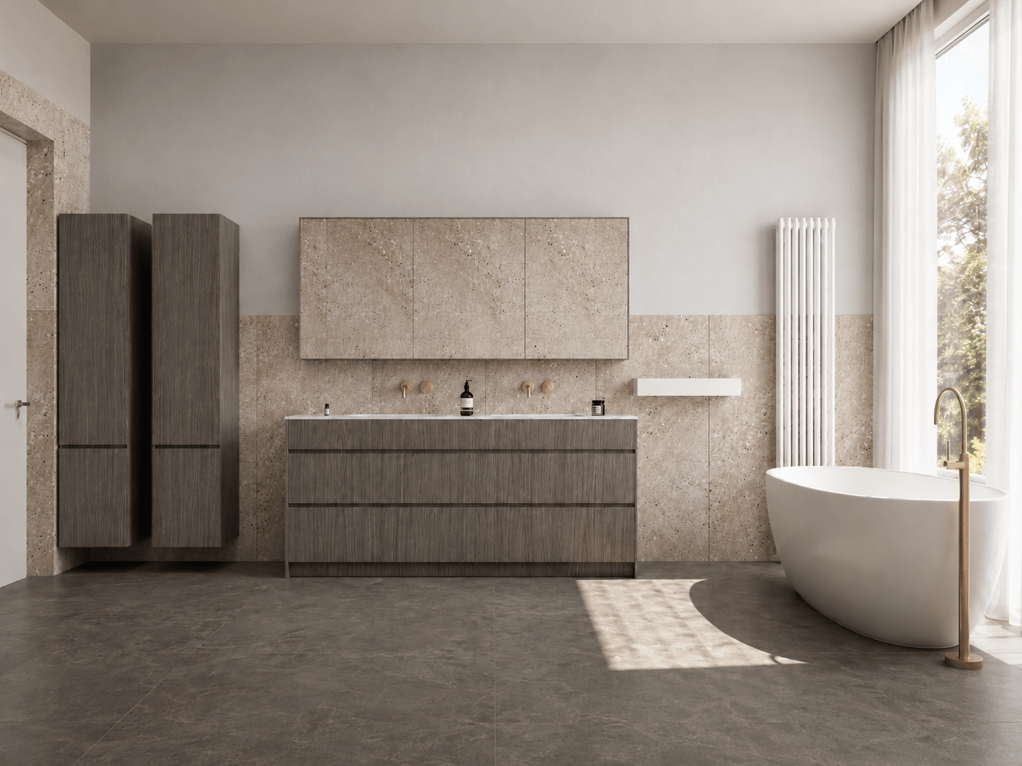 A wide view of a pale stone bathroom with dark timber vanity storage and a freestanding bath beside full-height glazing.
